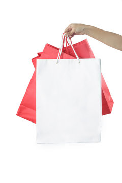 Hand with paper bags on the white background - studio shoot, shopping and consumerism concept
