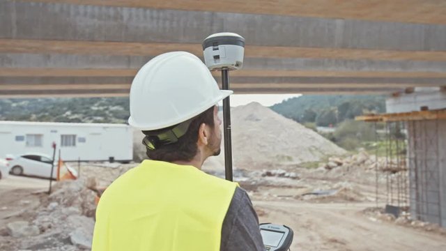 Construction supervisor inspecting a large road construction site using GPS equipment