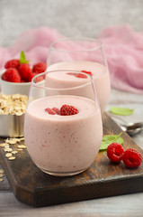 Raspberry and banana smoothie with oatmeal on the rustic wooden table, selective focus, vertical, copy space
