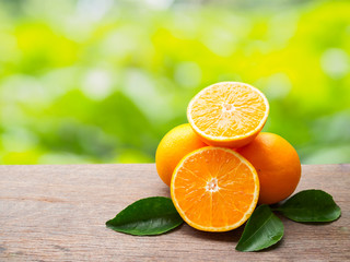 Pile orange fruit and orange slice with gren leaf on wooden tabl