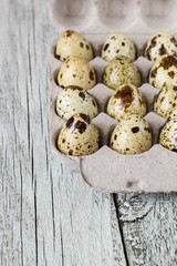 Cardboard egg rack wit quail eggs on wooden table
