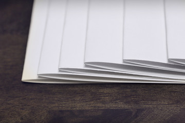 blank papers stack up on wooden table.