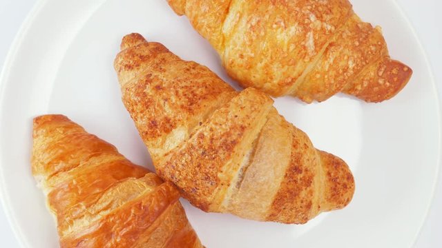 Background of three French croissants revolving on a stand on a white table