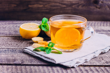 White cup of ginger tea with lemon, honey and mint. on gray tablebackground.