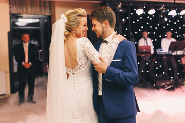 White smoke envelopes happy wedding couple dancing in the hall