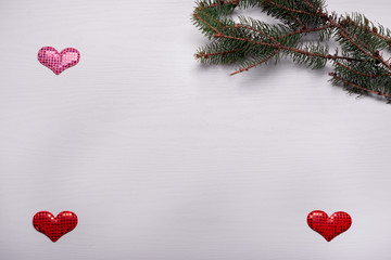 Wooden white background with a branch of pine and three hearts.