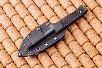 Black knife on wooden background.