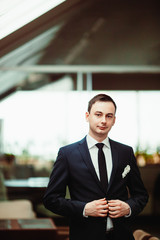 The handsome groom stands in the center of room