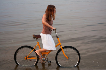 Fototapeta na wymiar The girl rides a bicycle on the water