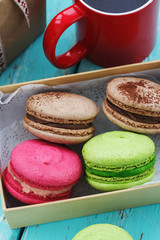 Macaroon cakes in a box and mug of tea with gift