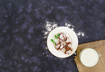 Chocolate cookies and a glass of milk on dark background. Top view