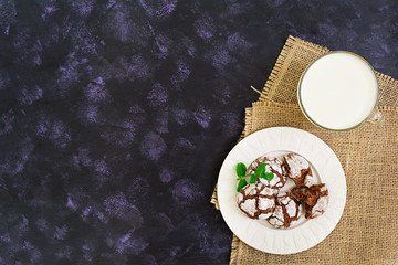 Chocolate cookies and a glass of milk on dark background. Top view