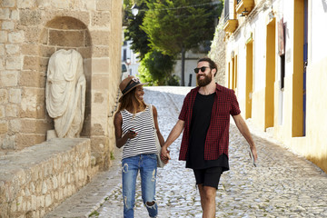 Happy couple on holiday hold hands walking in Ibiza, Spain
