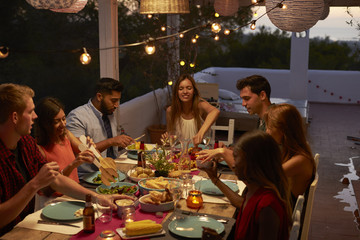 Friends talking at a dinner party on a patio, elevated view