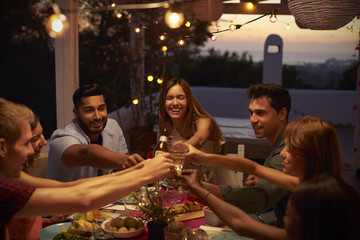 Friends make a toast at a dinner party on a patio, close up