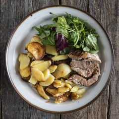 Baked meat with fried potatoes on a vintage plate