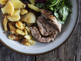 Baked meat with fried potatoes on a vintage plate