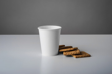 Some white cup with biscuit on gray table