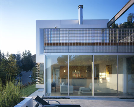 Exterior of a house in California, USA with living space through glass wall.