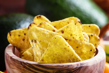 Corn nachos with salt in wooden bowl, old wooden background, sel