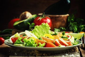Salad with avocado, salmon, lettuce, onions and peppers on a pla