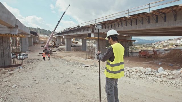 Construction supervisor inspecting a large road construction site using GPS equipment
