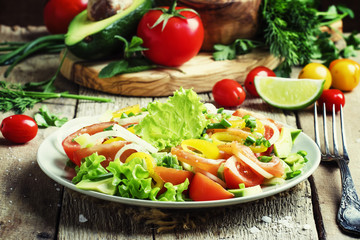 Salad with avocado, salmon, lettuce, onions and peppers on a pla