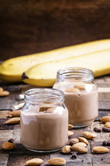 Chocolate almond smoothie in glass jars, old wooden background,