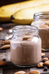 Chocolate almond smoothie in glass jars, old wooden background,