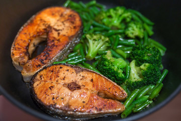 Grilled salmon steak with vegetables on frying pan: broccoli, green beans, tasty and healthy dinner.
