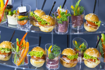 Mini desserts and meat canapes vegetable snacks in plastic cups canapes