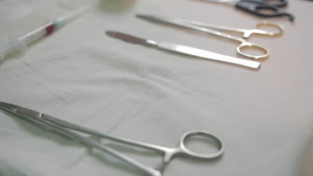 Closeup of four different stainless steel surgical forceps and scalpel isolated on white background. Hand the doctor takes off the table Hemostat.