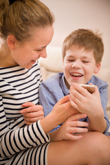 Portrait of smiling woman with cute kid boy looking into a smartphone and laughing. Mother with child with telephone. Happy family. Technology and communication concept