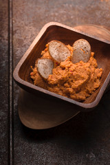 Hummus in the wooden bowl on the old metal background vertical