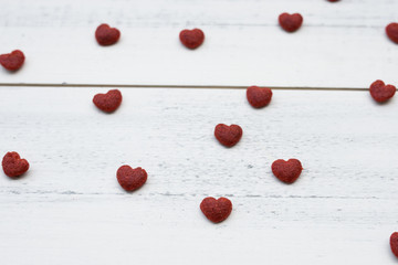 Naklejka na ściany i meble Red little hearts on white wooden background, selective focus on the heart in the center