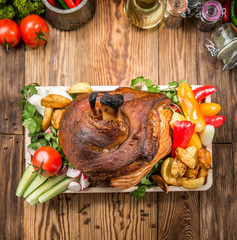 Roasted sliced pork ham and roast vegetables on dark rustic background