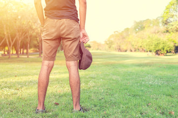 Man standing on grass holding a hat