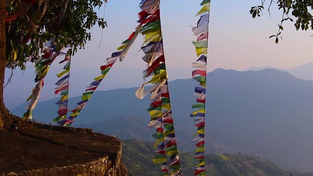 Prayer flags fluttering in the wind with mountains in the background.