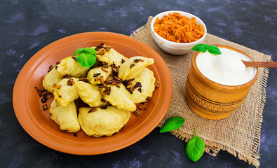 Delicious dumplings with cabbage and sour cream on dark background