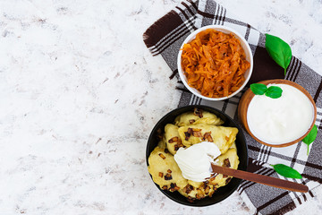 Delicious dumplings with cabbage and sour cream on white background. Top view
