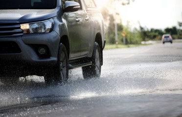 Motion car rain big puddle of water spray from the wheels through flood water after hard rain.Stop...