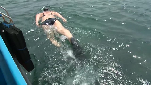 Girl in swim suit and diving mask jump in water snorkeling, floating on water surface and turn to camera. sexy butt, legs above the water, Bali, Indonesia, top view
