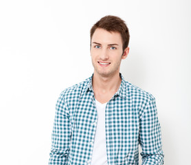 Happy young man. Portrait of handsome young man in casual shirt keeping arms crossed and smiling while standing against white background