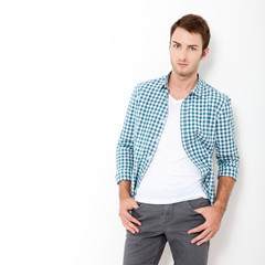 Fototapeta premium Happy young man. Portrait of handsome young man in casual shirt keeping arms crossed and smiling while standing against white background