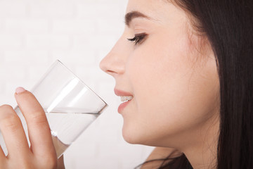 Girl drinking water at home. Glass of water in morning before breakfast.