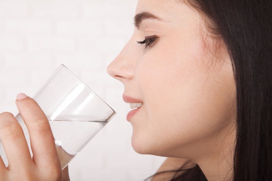 Girl drinking water at home. Glass of water in morning before breakfast.