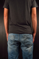 Back of young man wearing grey blank t-shirt, standing in a stud