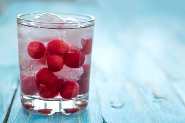 Cold water with ice, cherries and berries.