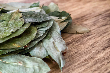 Batch of coca leaves on wooden table. Used in countries like Peru and Bolivia to combat altitude...