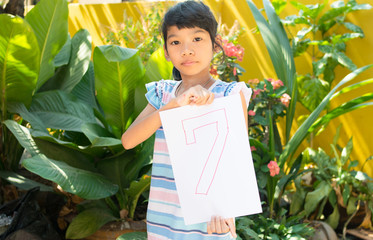 number concept,girl holding number seven on white paper